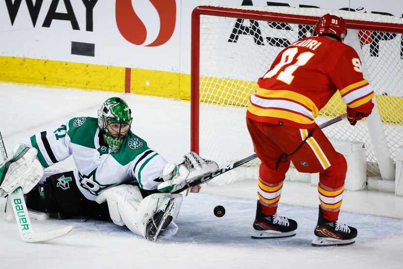 Dallas Stars goalie Scott Wedgewood, left, looks back as Calgary Flames forward Nazem Kadri...