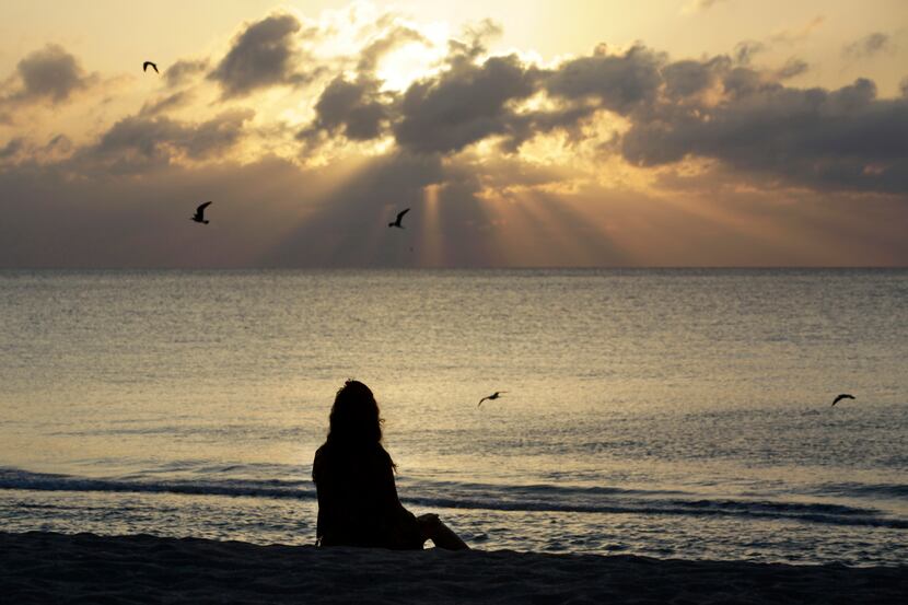 A woman meditates on the beach in Miami Beach, Fla., on Wednesday, April 28, 2010. According...