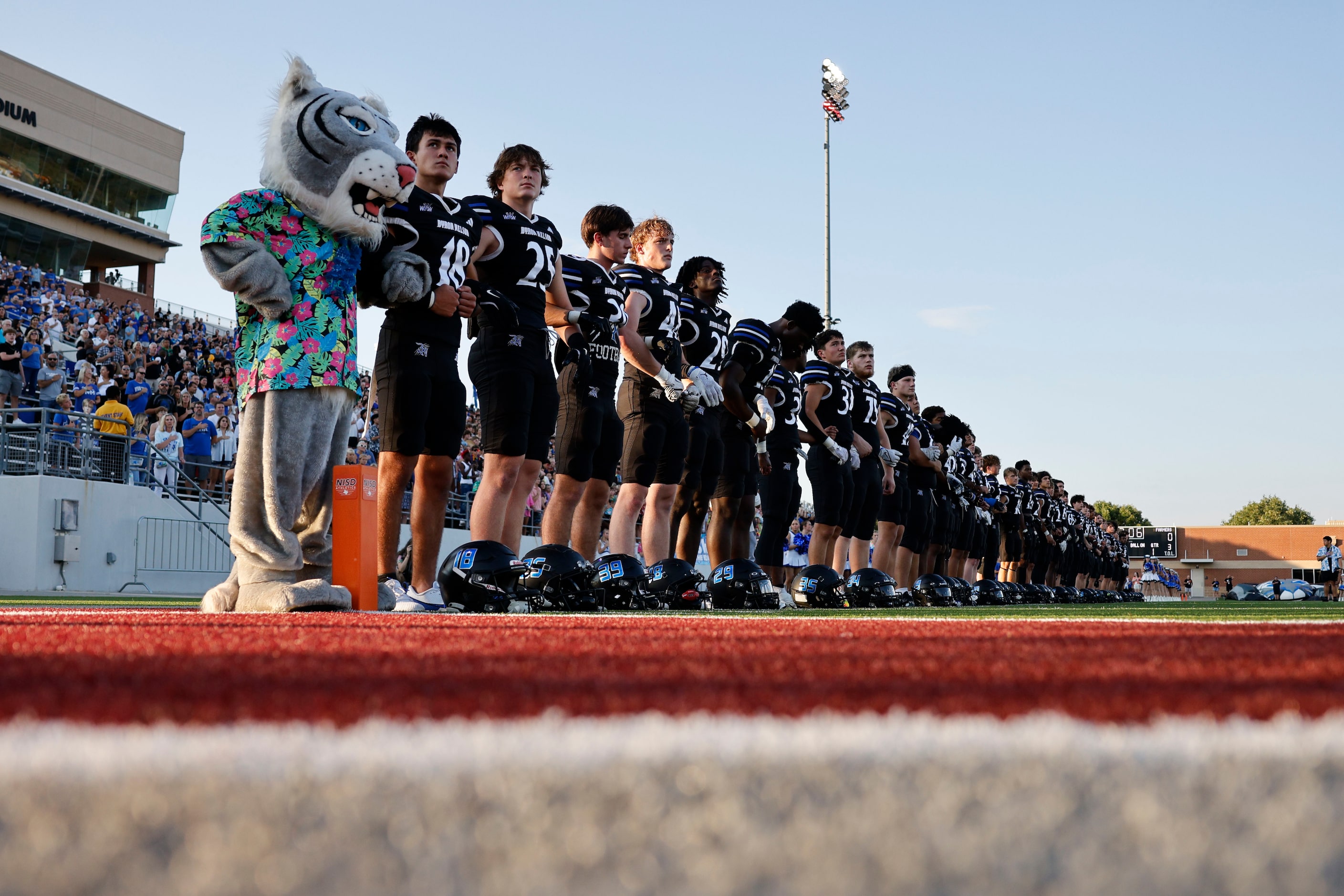 Byron Nelson's players line up for the national anthem before a high school football game...