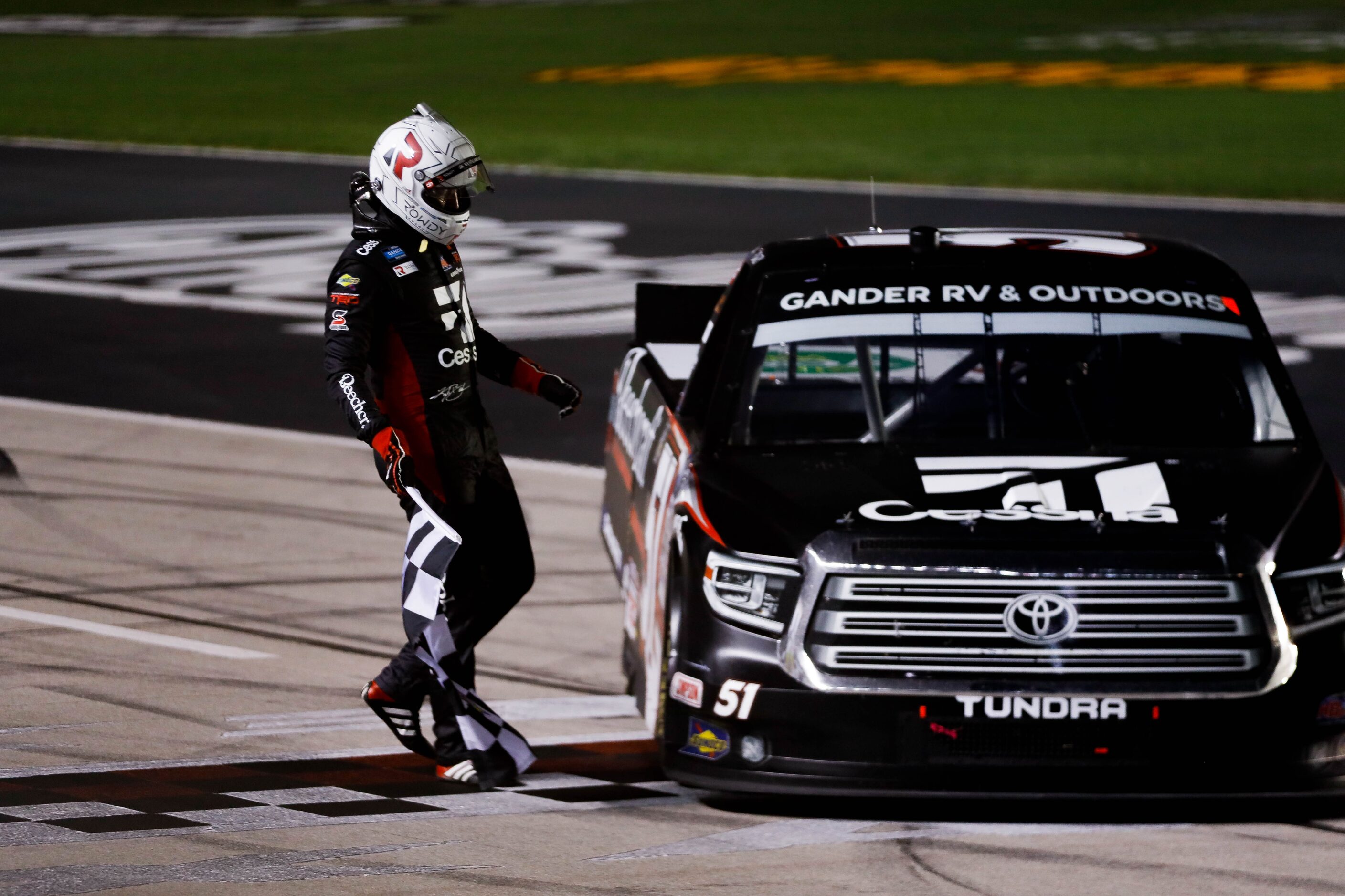 Driver Kyle Busch (No. 51) holds the race flag after winning the Vankor 350 NASCAR Gander RV...