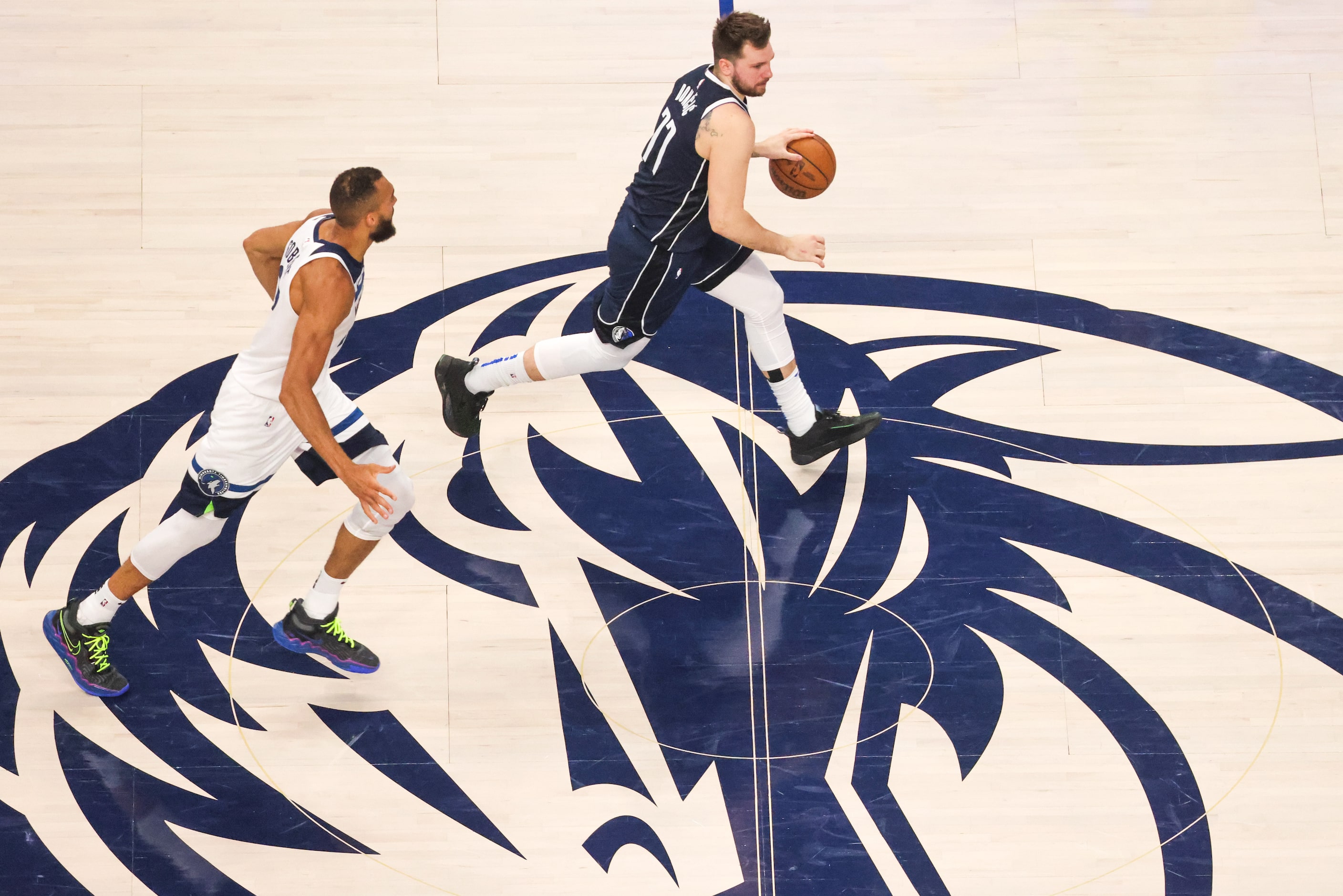 Dallas Mavericks guard Luka Doncic (right) brings the ball up the court past Minnesota...