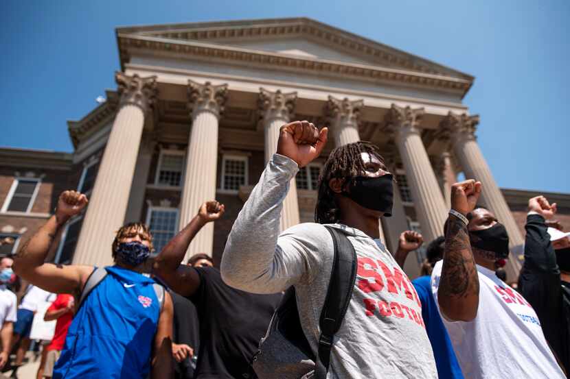 SMU football player Brandon Crossley, center, puts his fist in the air with other Black...