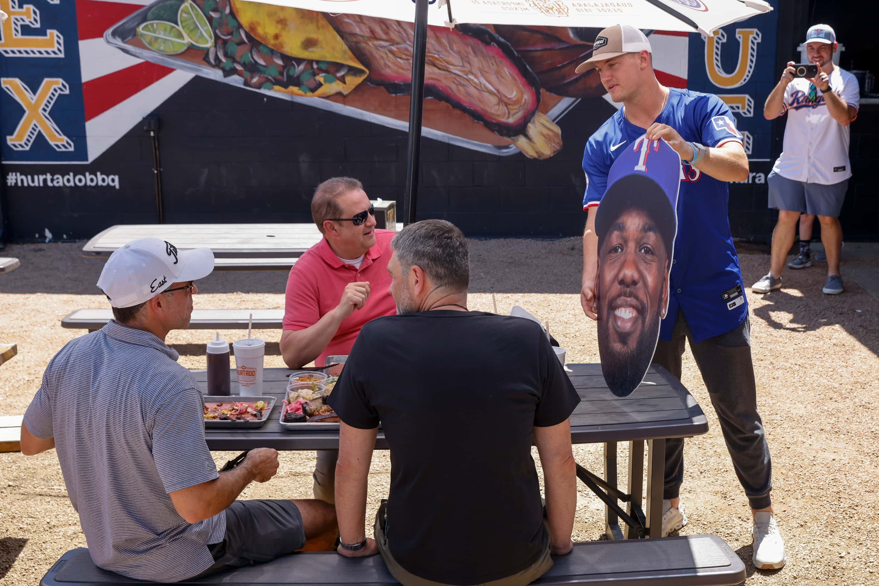 Texas Rangers third baseman Josh Jung gives a cutout of Adolis Garcia to customers at...