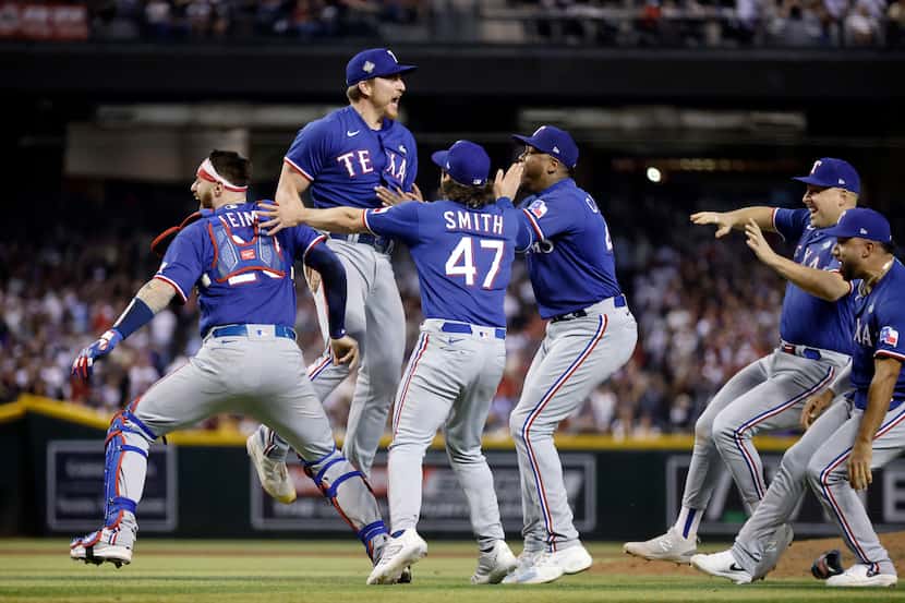 Texas Rangers relief pitcher Josh Sborz (center) leaps into the arms of his teammates after...