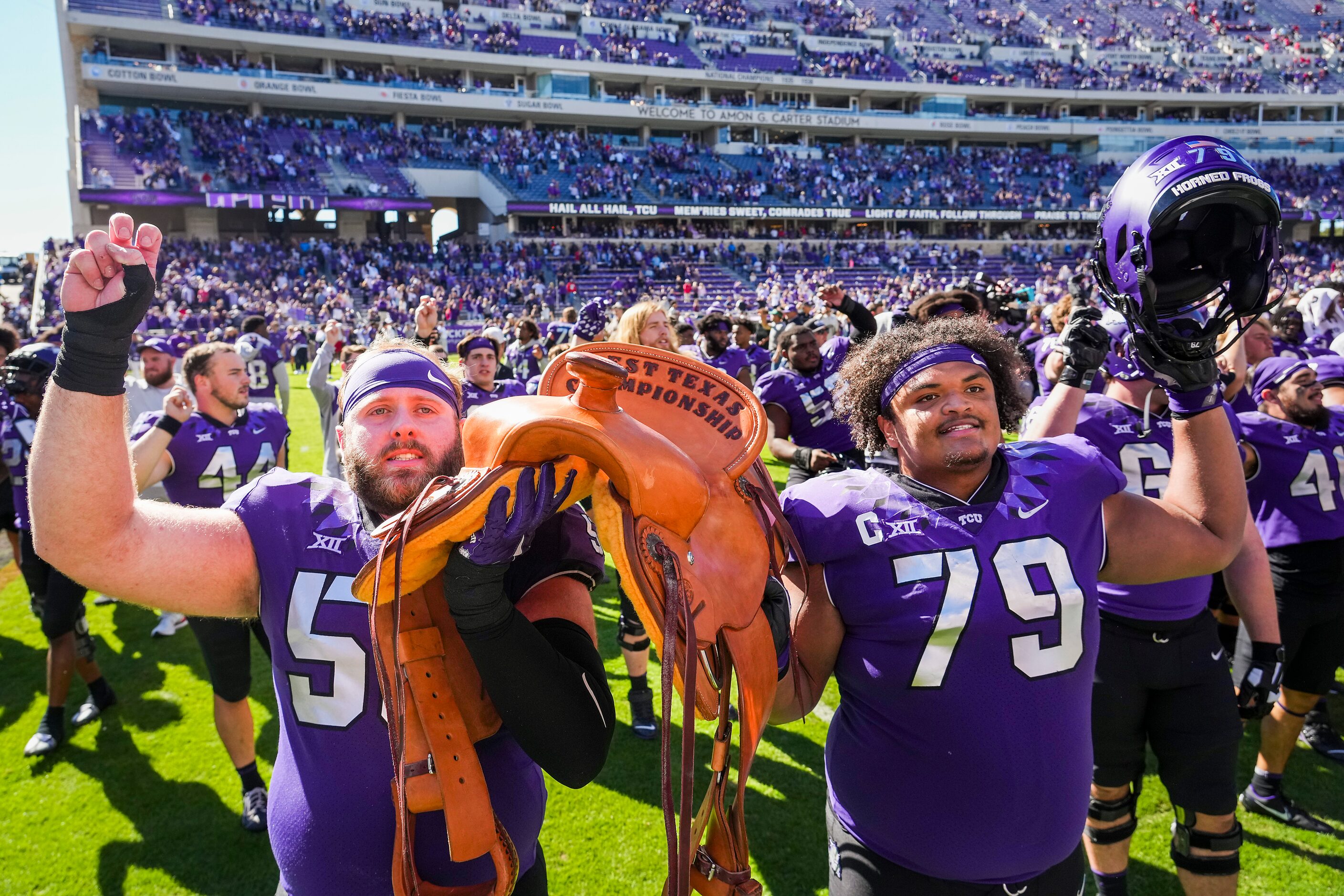 TCU offensive linemen Alan Ali (56) and Steve Avila (79) hoist The Saddle Trophy after a...