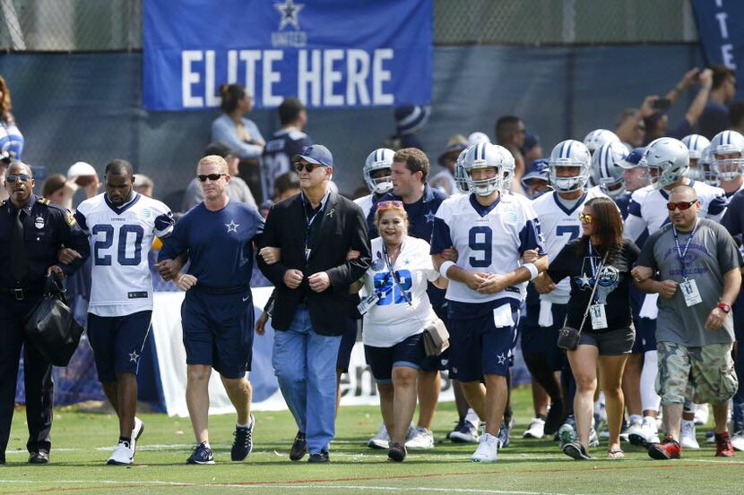 Dallas Mayor Mike Rawlings, center, walks arm-in-arm with Dallas Cowboys coach Jason...