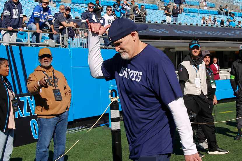 Dallas Cowboys defensive coordinator Dan Quinn motions to fans before an NFL game against...
