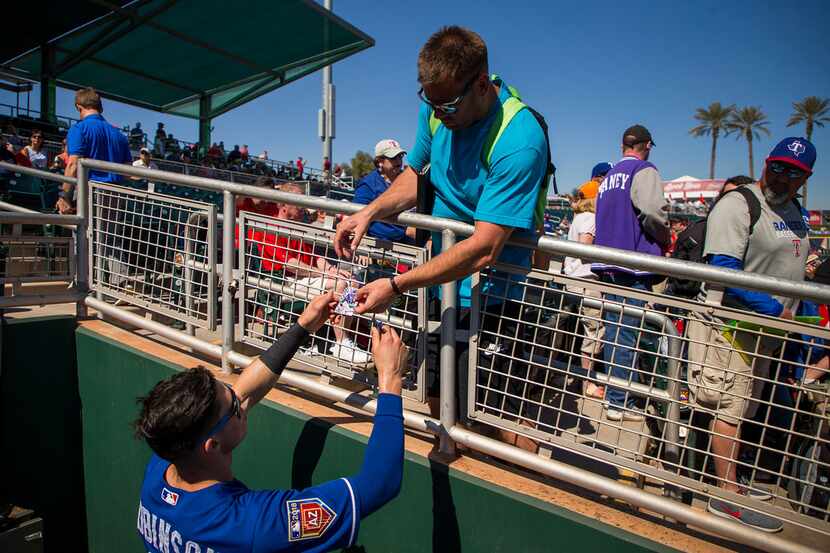 Texas Rangers infielder Drew Robinson signs autographs for fans before a spring training...