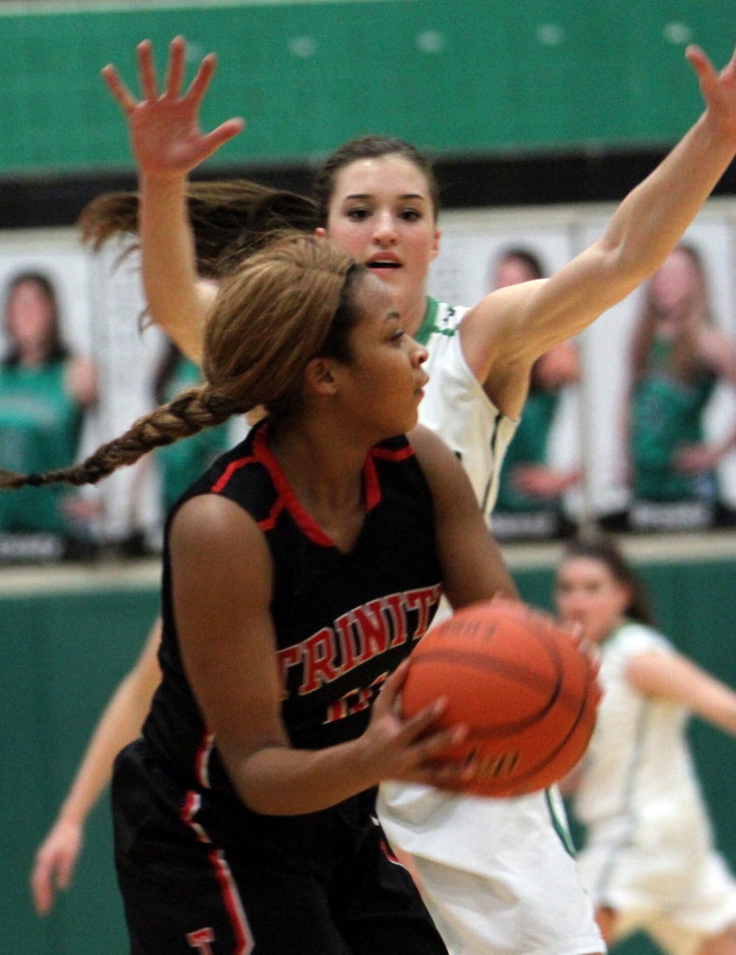 Euless Trinity guard Te ana Washington (11) looks for an open teammate as she is defended by...