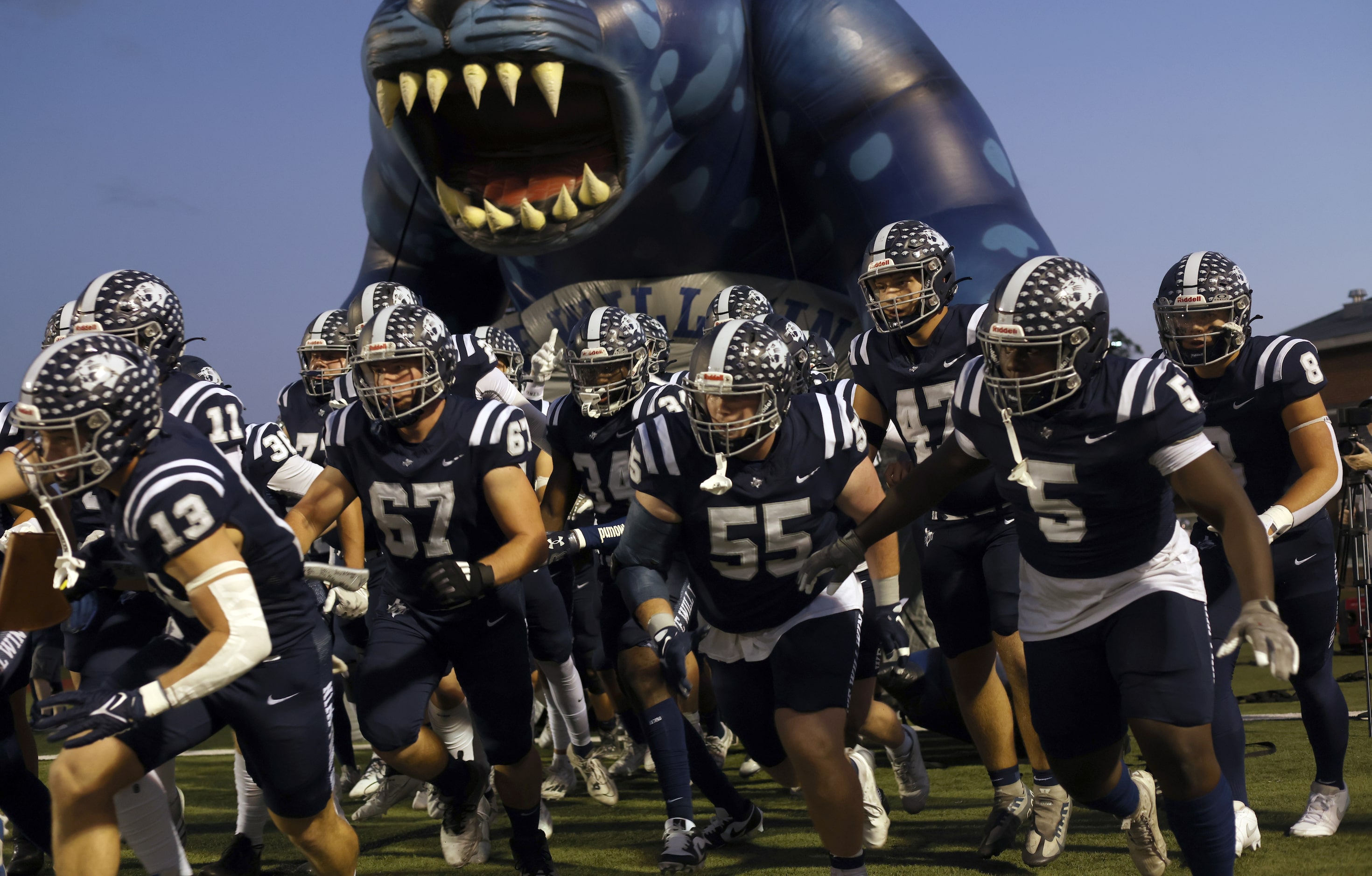 Flower Mound players bolt from the team inflatable mascot before the start of their game...