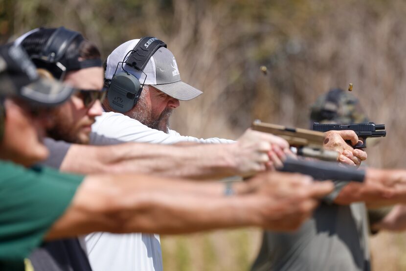 John Wolfe (back), pastor of CrossRidge Church, Little Elm, takes part in a firearm...