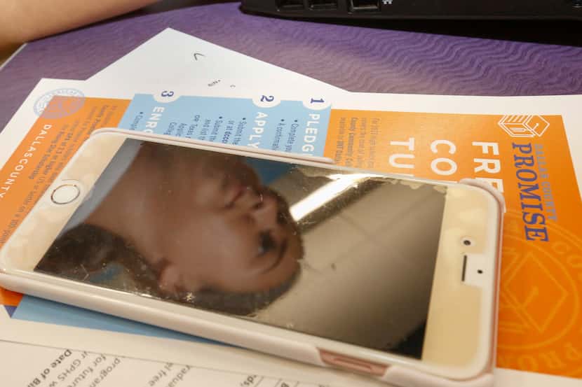 Grand Prairie High School senior, Briana Rocha, is reflected in her cellphone screen as she...