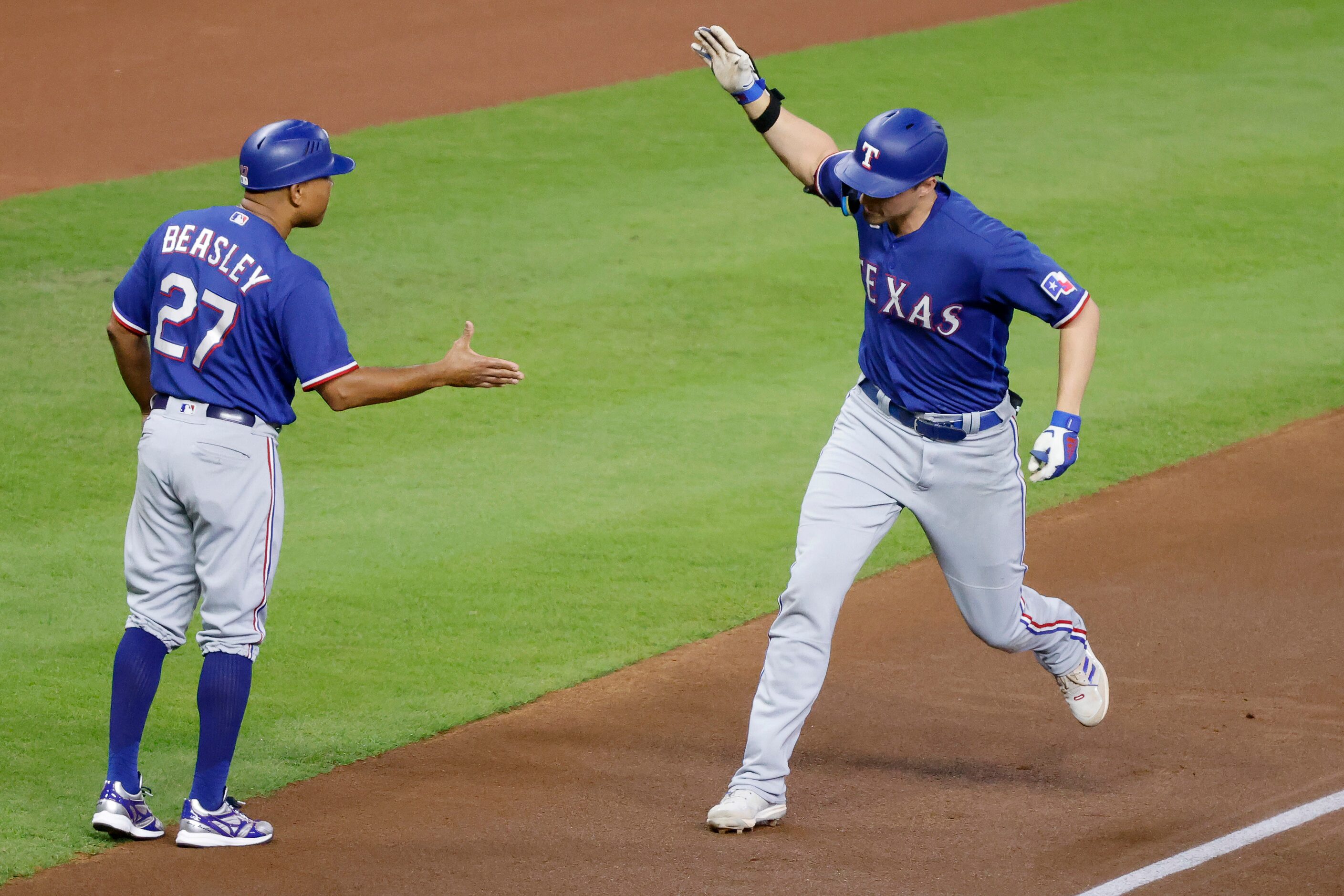 Texas Rangers Corey Seager slaps hands with third base coach Tony Beasley following his...