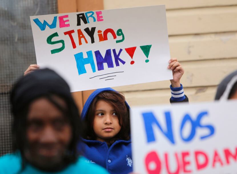 Juan Pina, a 10-year-old West Dallas resident, holds a sign outside a rental house owned by...