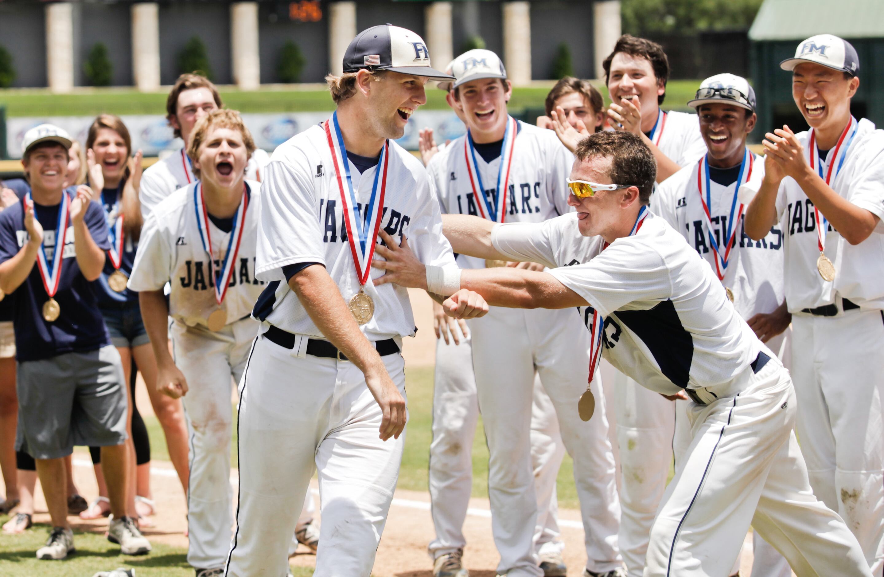 Flower Mound player Seth Jordan (16, center left, facing camera) is cheered on by his...