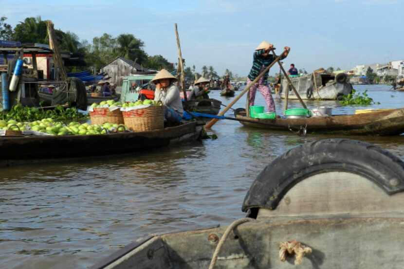 A farmer paddles his sampan through the Phong Dien retail market, an intimate retail market...