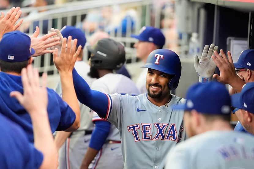 Texas Rangers' Marcus Semien celebrates with teammates in the dugout after hitting a solo...