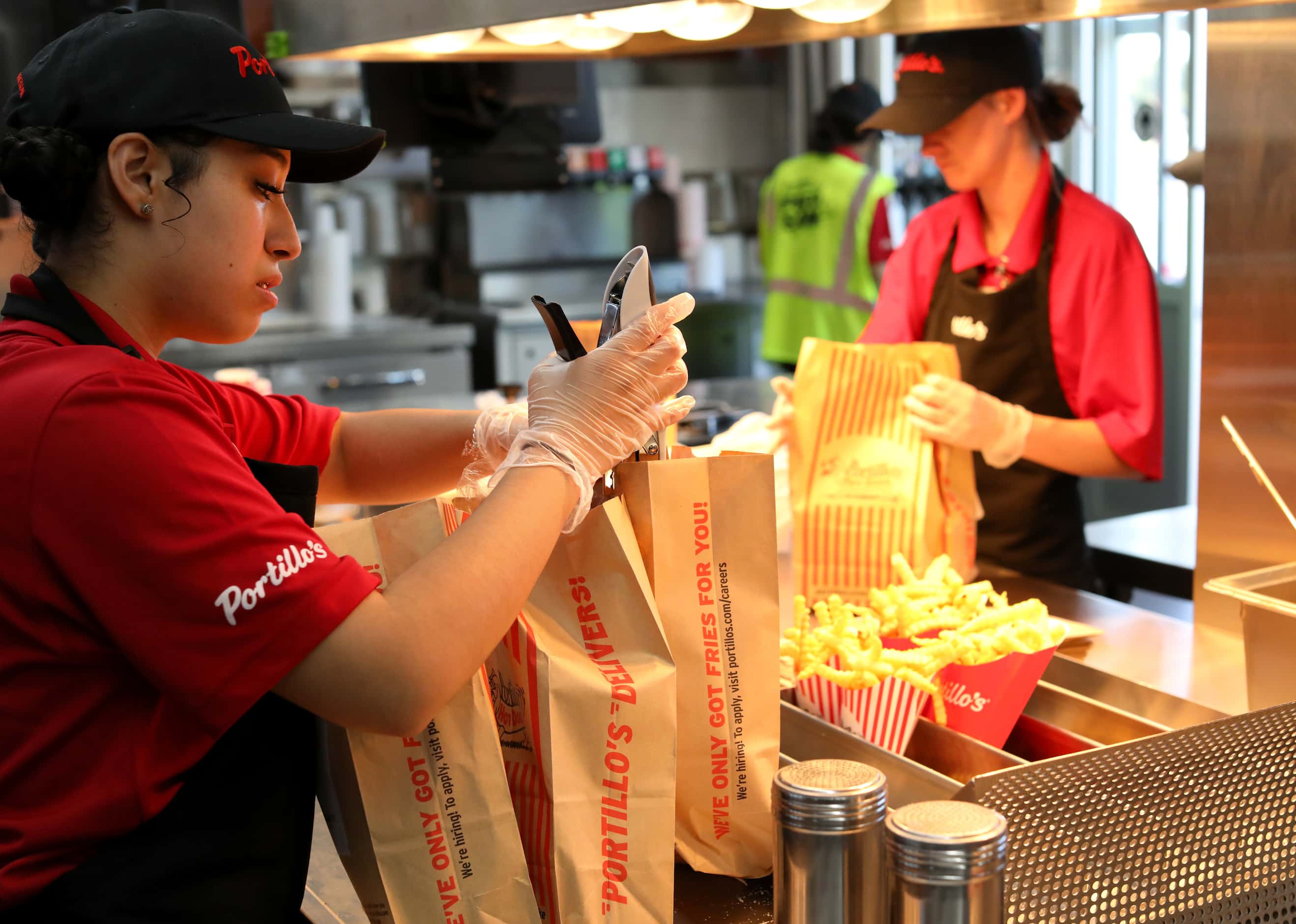 Brianna Fuentes, left, bags fries at Portillo's in Allen on opening day.