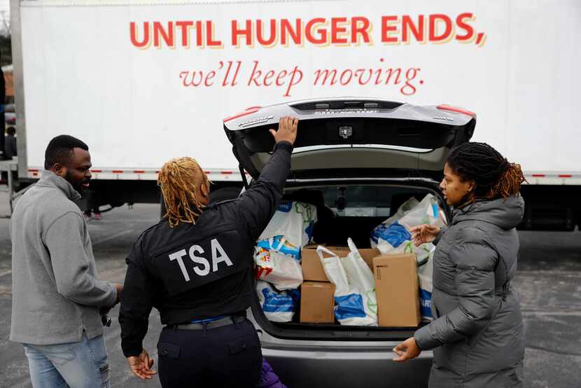 TSA employee Princess Young, center, loads food into a car after visiting a food pantry for...