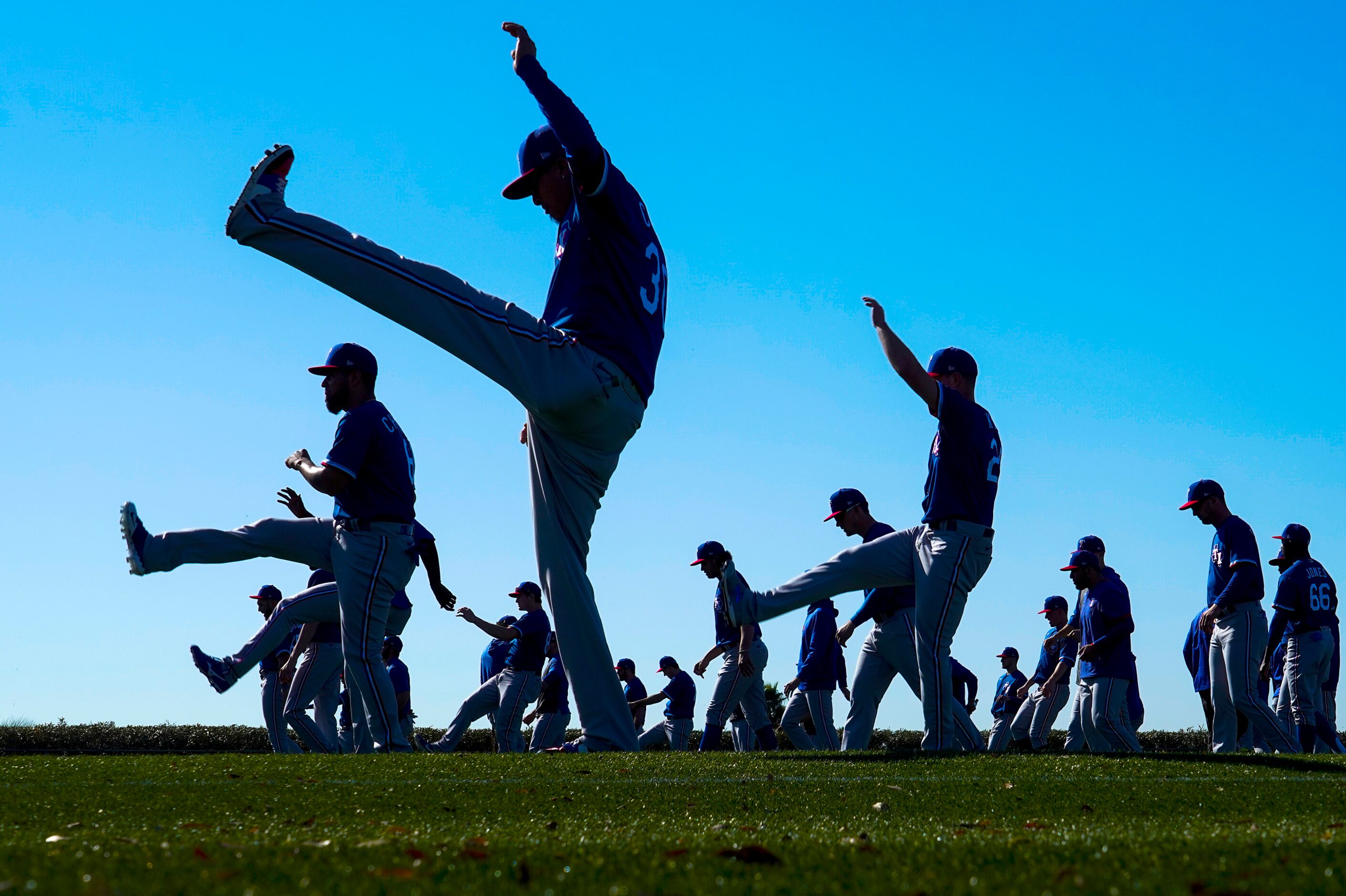 Texas Rangers pitchers and catchers, including pitcher Jesse Chavez (front) stretch on a...