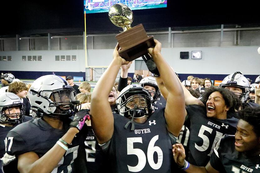 Guyer High School defensive lineman Dynell Neal (56) hoists up the trophy after the win as...