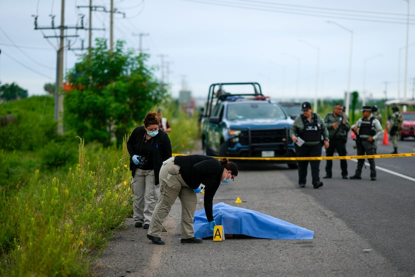 Crime scene investigators work at the site where a body was found lying on the side of a...