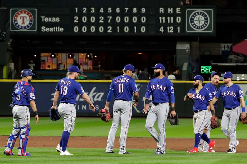 Texas Rangers players react on the field after they beat the Seattle Mariners 11-4 in a...