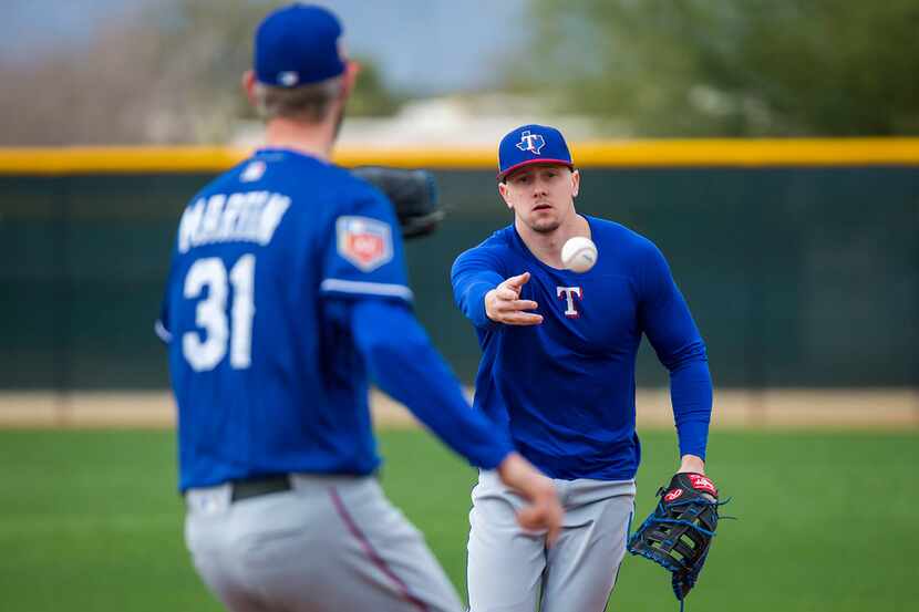 Texas Rangers outfielder Ryan Rua tosses a ball to pitcher Chris Martin as he works at first...