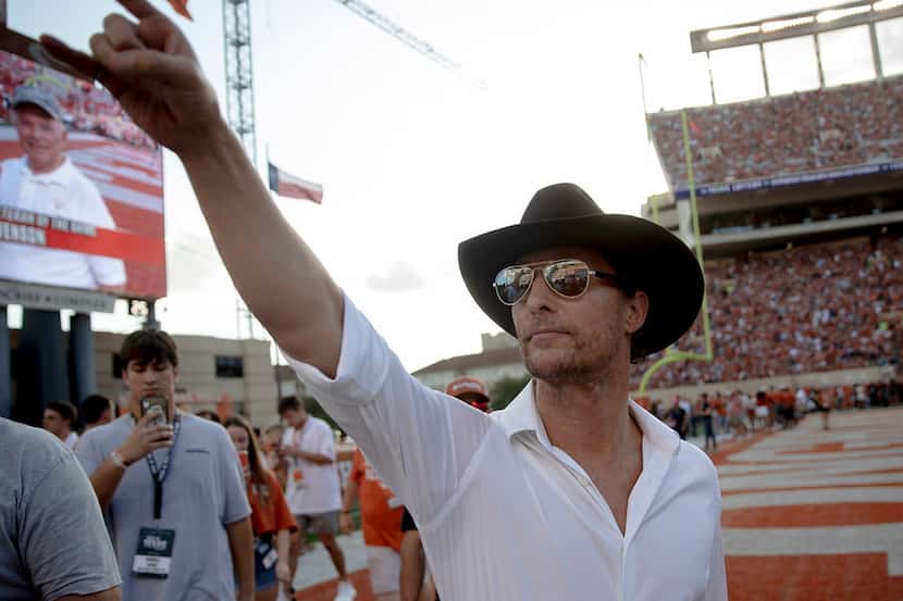 Actor Matthew McConaughey holds up the "Hook 'Em Horns" sign to Texas fans before a game...