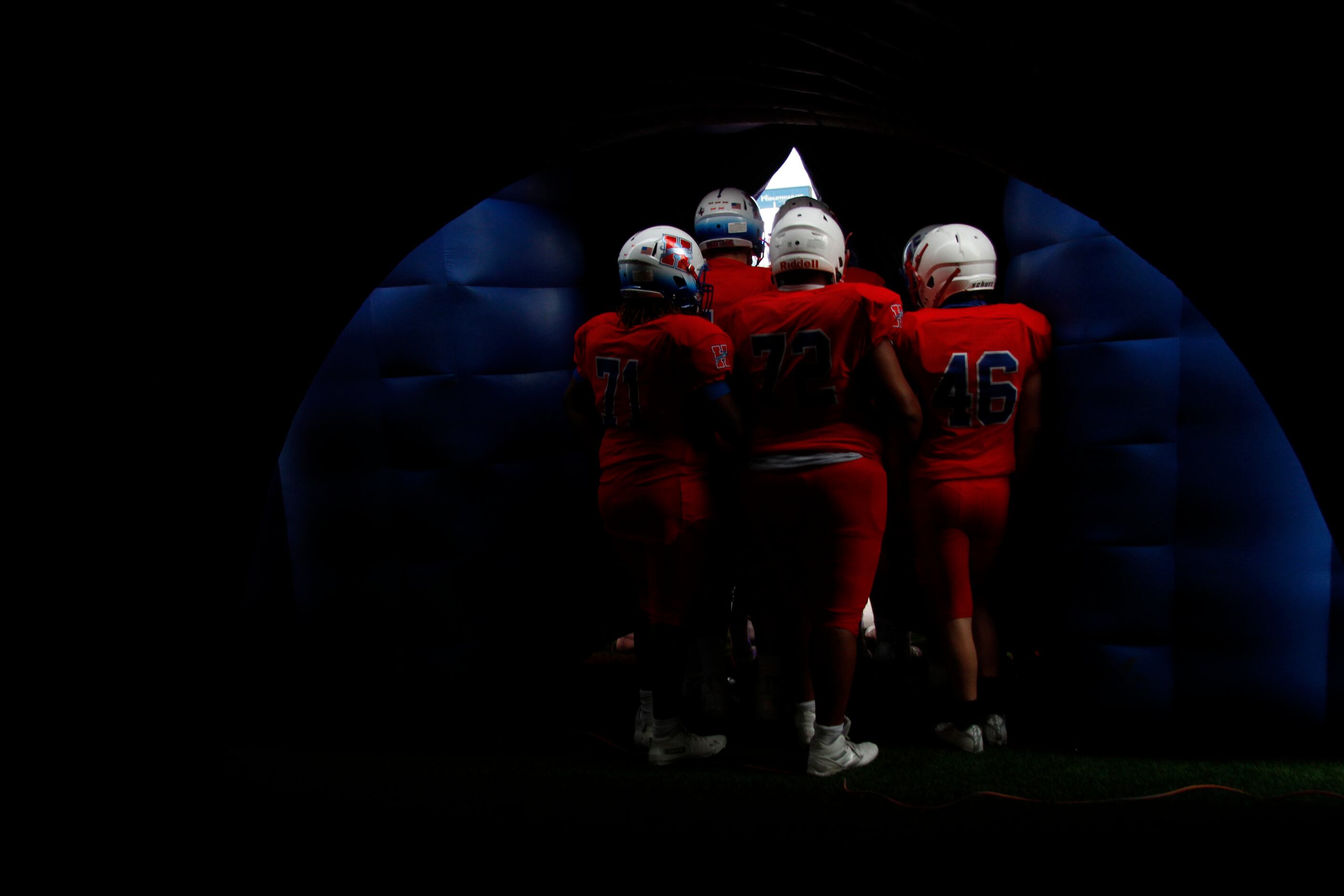 Midlothian Heritage players huddle near the opening of the team's inflatable as they await...
