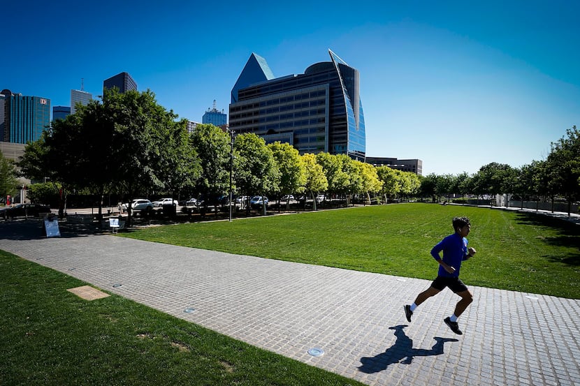 A runner has room to glide through the relatively empty Klyde Warren Park on Monday...