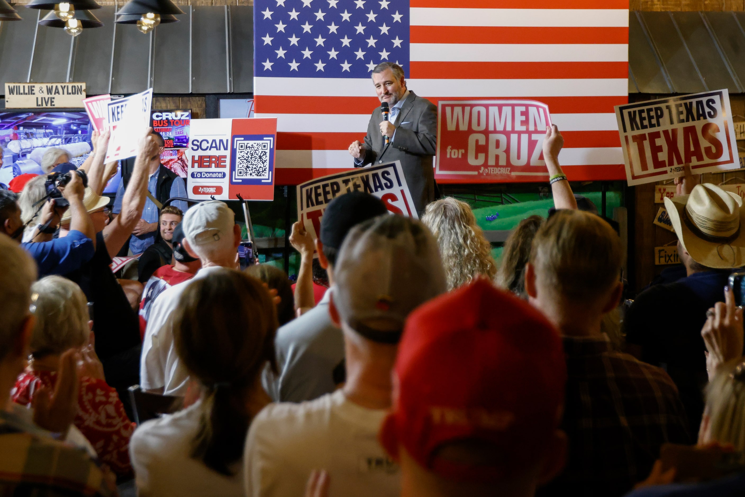 People raise signs as Senator Ted Cruz (R-Texas) speaks during a campaign rally at Outpost...