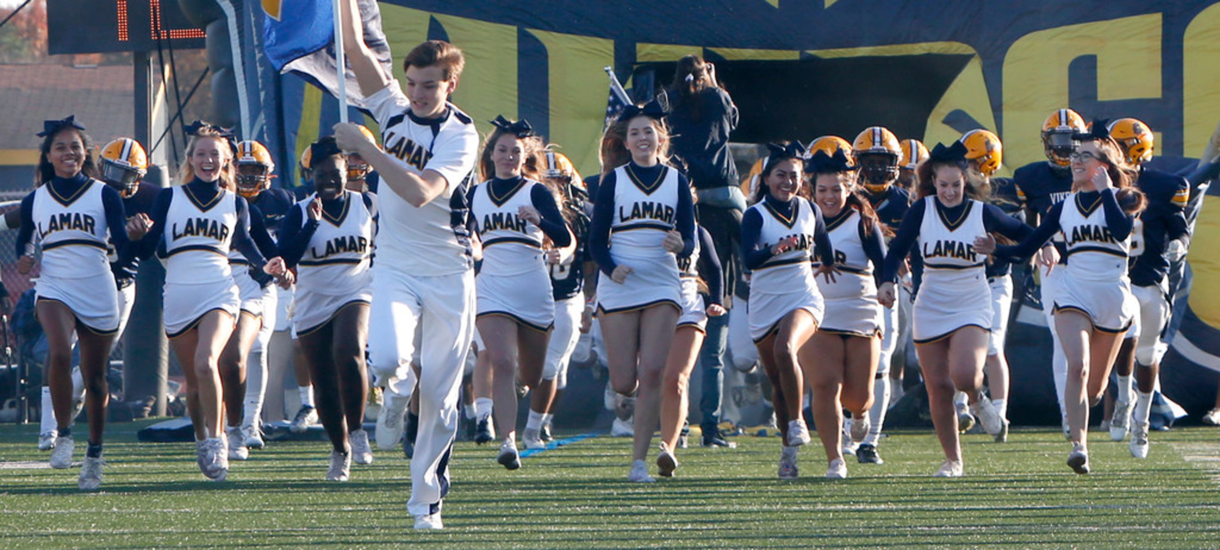 Members of the Arlington Lamar cheerleaders storm the field as they lead Vikings players...