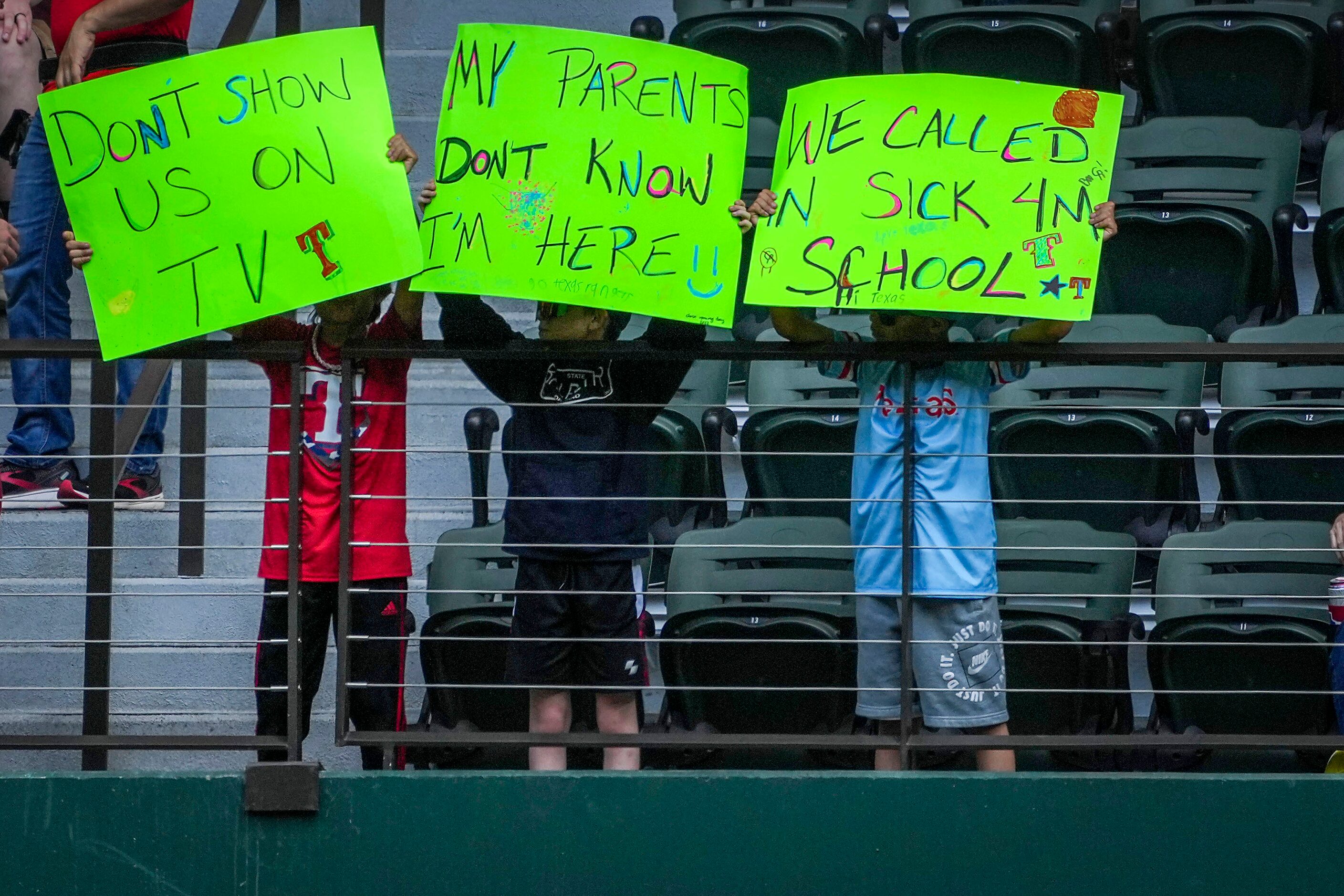 Texas Rangers fans hold signs before the Rangers home opener against the Colorado Rockies at...