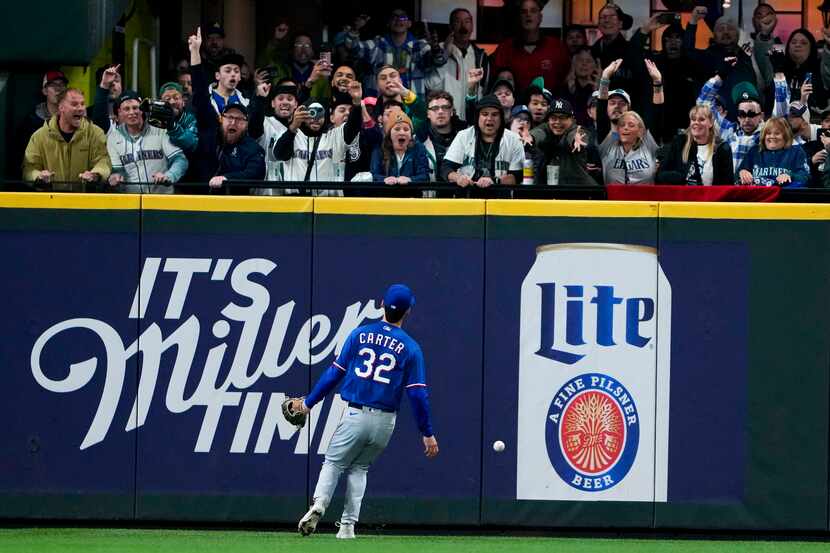 Texas Rangers left fielder Evan Carter watches the game-winning, two-run double by Seattle...