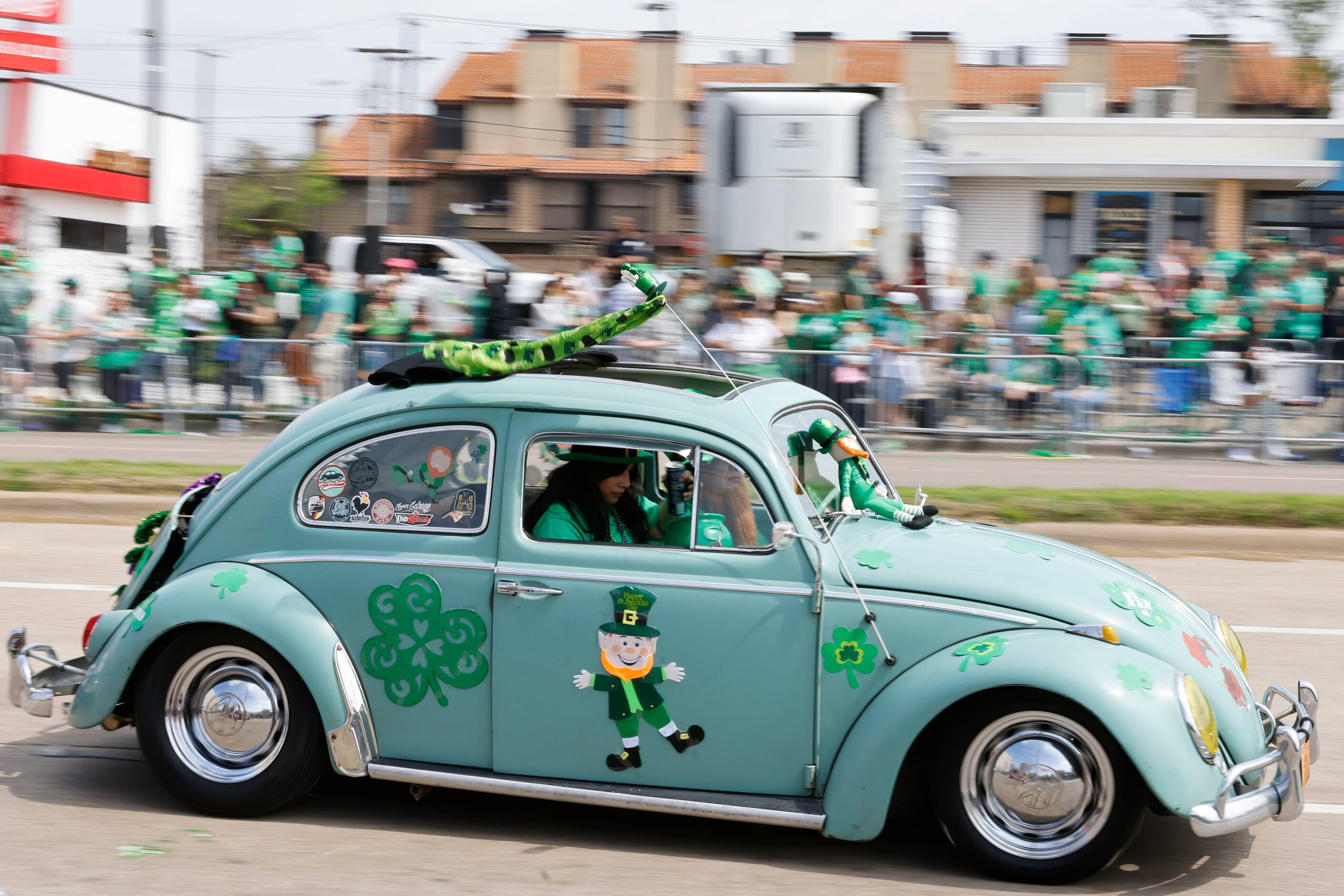 Volkswagen Beetles drive down the route during a Saint Patrick's Day parade on Saturday,...