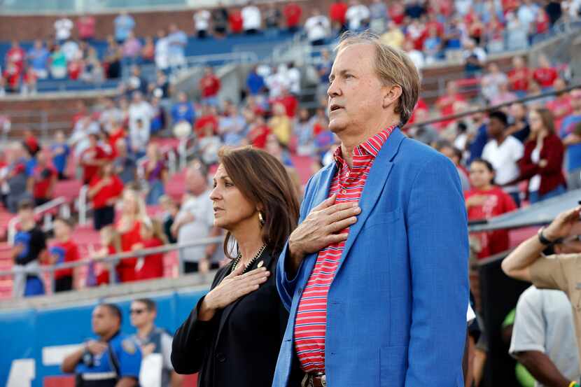 Texas Attorney General Ken Paxton sings the national anthem alongside his wife Angela Paxton...