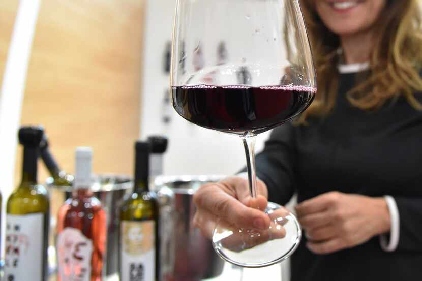 A woman hands a glass of wine from the "Le Moire" wine maker of the Italian Calabria region...