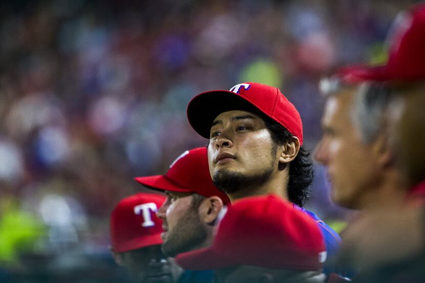 Texas Rangers pitcher Yu Darvish (11) watches from the dugout during the fifth inning of...