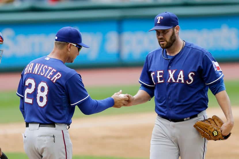 Texas Rangers starting pitcher Colby Lewis, right, hands the ball to manager Jeff Banister...
