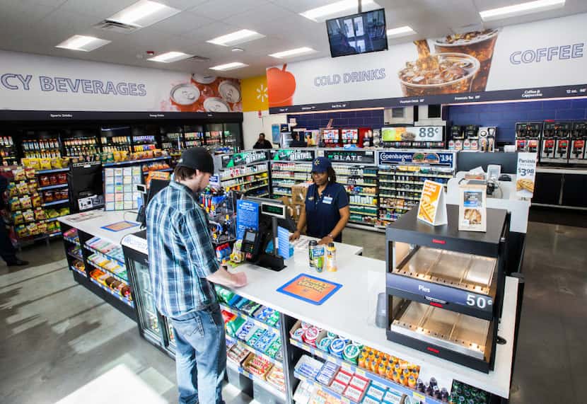 Cashier Monica Betts helps a customer inside a new Walmart convenience store on Wednesday,...