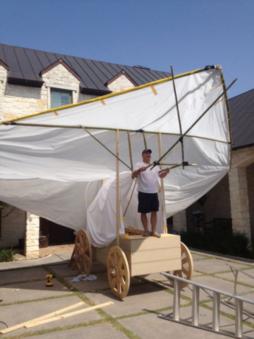 John Leonard works on constructing the family's covered wagon, which is topped with a hang...