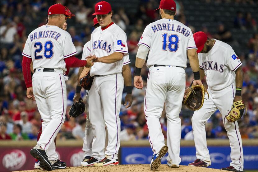 Texas Rangers starting pitcher Derek Holland (45) hands the ball to manager Jeff Banister...