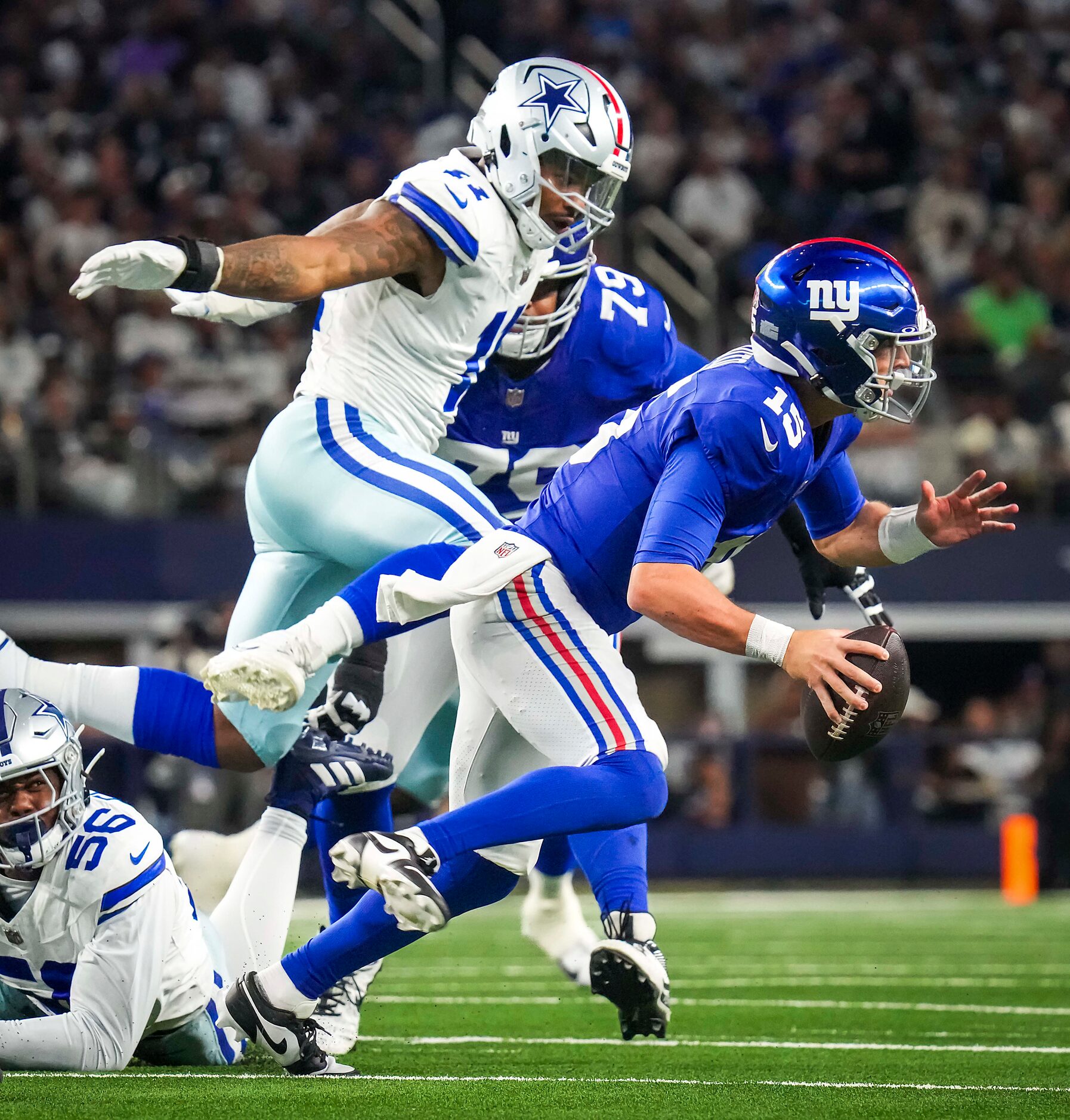 New York Giants quarterback Tommy DeVito (15) scrambles away from Dallas Cowboys linebacker...