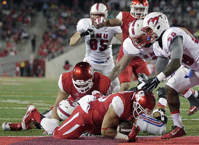 Houston running back Kenneth Farrow dives past SMU defenders for a touchdown during the...