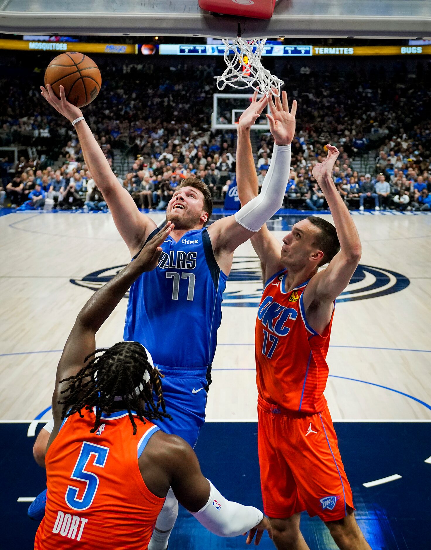 Dallas Mavericks guard Luka Doncic (77) drives to the basket between Oklahoma City Thunder...