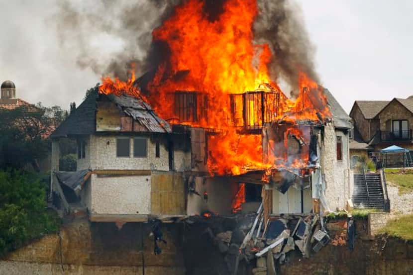 
Flames continue to burn in the ruins of a Lake Whitney luxury home demolished Friday in a...