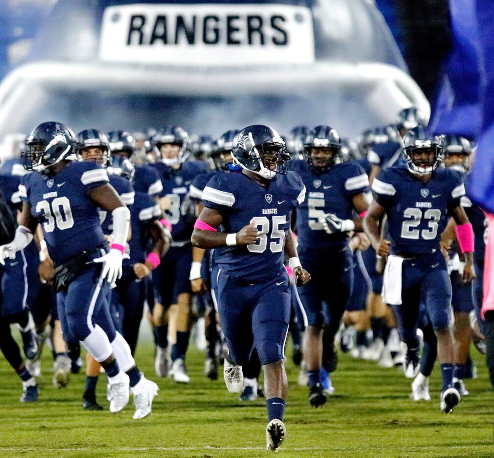 Lone Star High School middle linebacker Isaiah Foster (35) runs onto the field with his team...