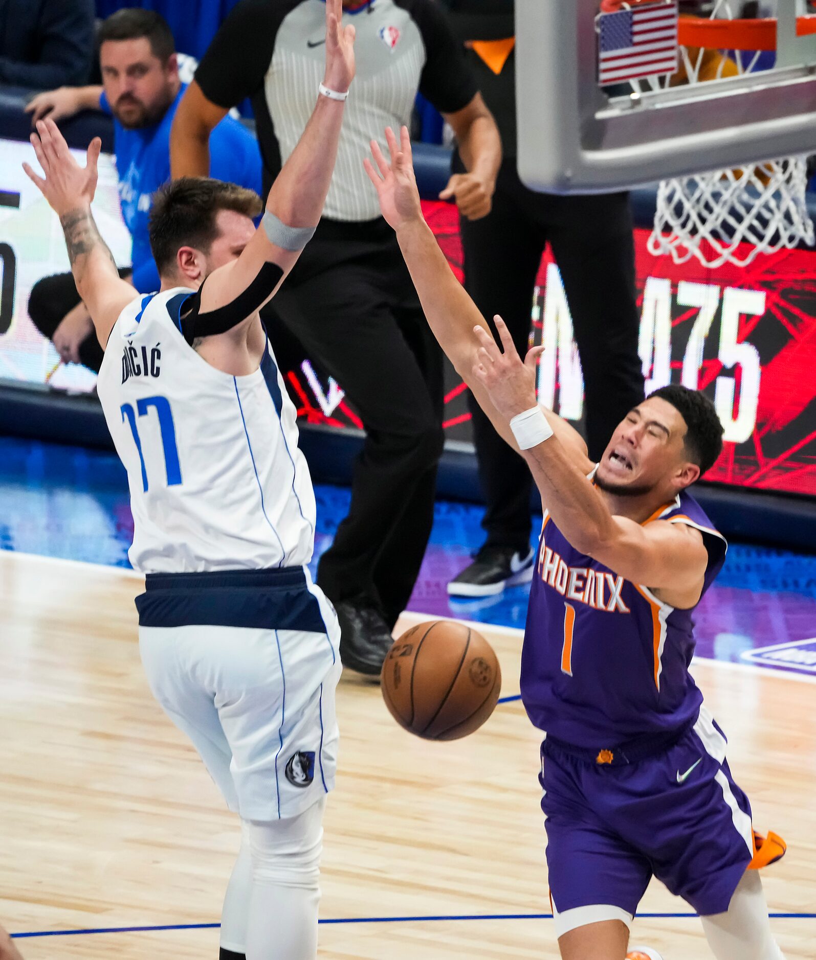 Phoenix Suns guard Devin Booker (1) is fouled by Dallas Mavericks guard Luka Doncic (77)...