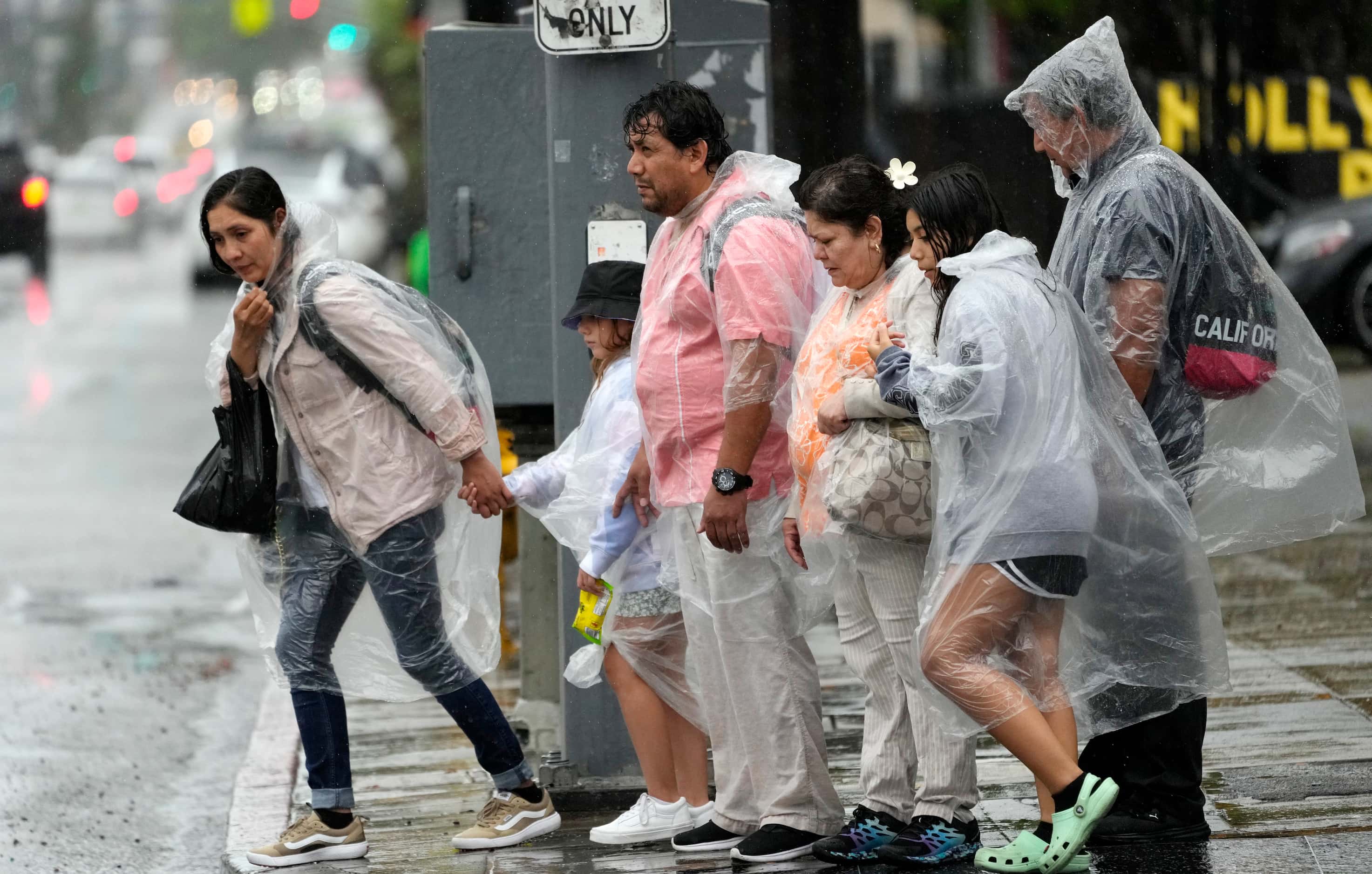 Pedestrians fight strong winds and rain on Hollywood Boulevard during Tropical Storm Hilary,...